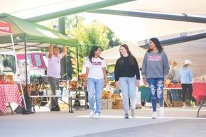 Students walk through a downtown farmers market