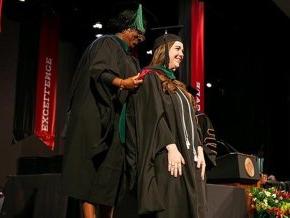 A graduate student is hooded at commencement