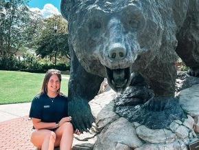 Kristi Hilton poses with the black bear statue on campus