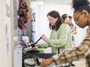 Students laddle soup into bowls inside