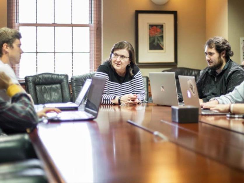 Student investors talk with professor seated around a conference table