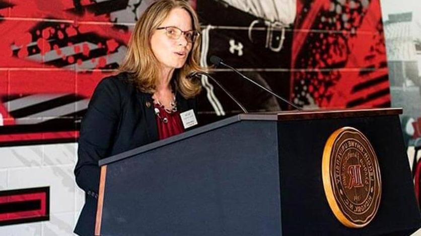 Athletic Director Kim Pate speaks at a podium unveiling the center